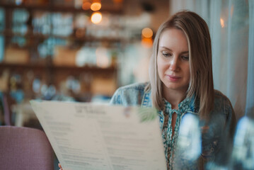 Woman is looking at menu in restaurant.
