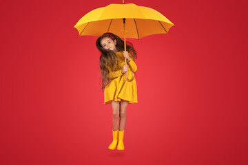 Happy emotional girl laughing with umbrella on colored red background. Autumn, spring season.