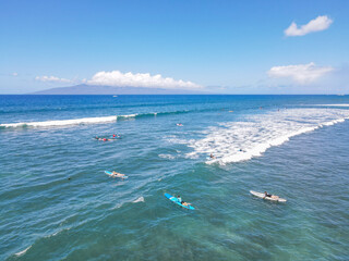 Aerial pic of surfers seating on surfboards and waiting for wave in the middle of ocean with perfect weather and clean water in Hawaii paradise, shot on drone from above 