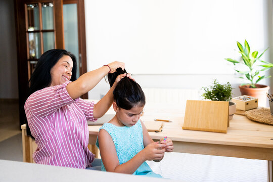 Mother combing to her daughter at home