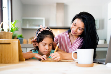 Latin mother helping her daughter do homework 