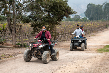 Women and men on ATVs are enjoying a ride in a field