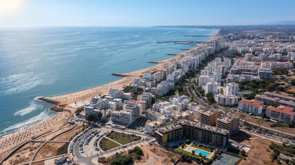 Fototapeta premium Beautiful aerial cityscapes of the tourist Portuguese city of Quarteira. On the seashore during the beach season with tourists who are sunbathing.