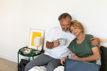 Senior couple in love drinking coffee on the bed