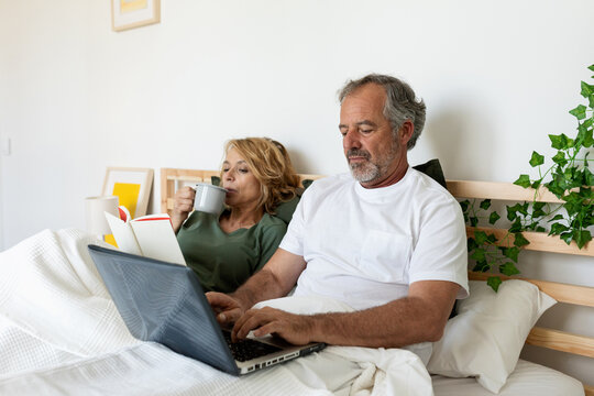 Senior couple relaxing and drinking coffee on the bed