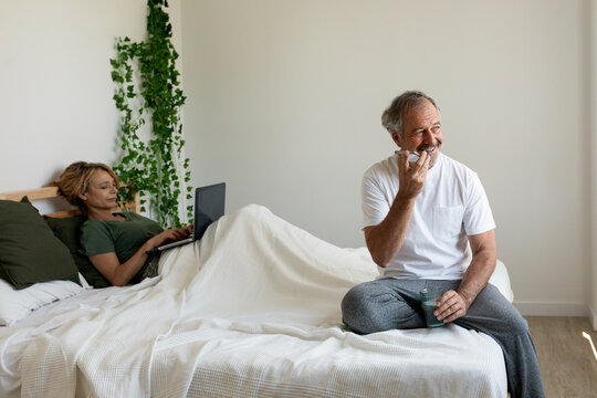 Senior couple relaxing using electronics at bedroom