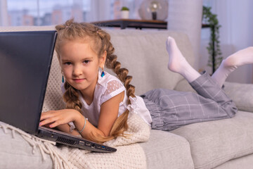 A school student, a little girl working on a laptop, enjoys using technology in teaching. Use of modern devices for educational purposes