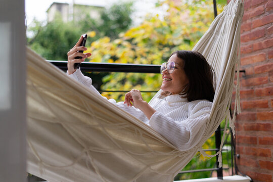 young woman talking in a videocall on a hammock