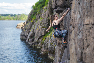 Obraz premium A girl climbs a rock above the water