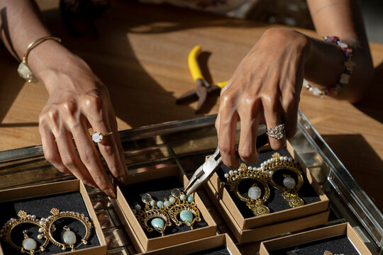 dark woman hands with tools over crafted jewelry