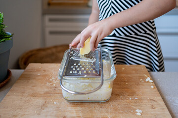 Child grating cheese using a manual grater at kitchen