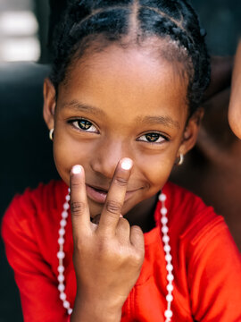 pretty african little girl sitting with victory sign looking at camera