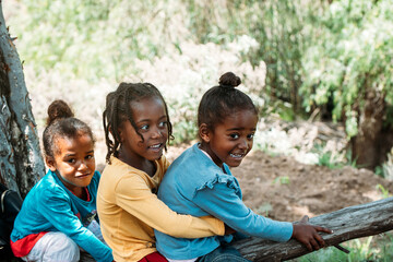 Group of black children having fun over a tree trunk in forest