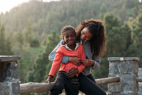 African little girl with mum sitting in fence