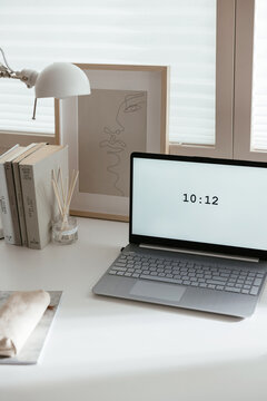 Laptop with digital clock near books and decorations
