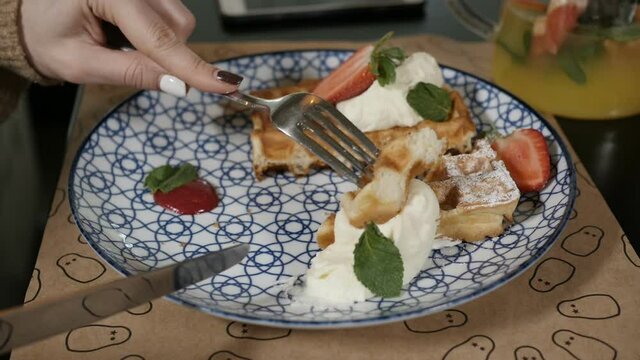 women's hands appetizing cut waffles with fruit and dip in cream. High quality FullHD footage