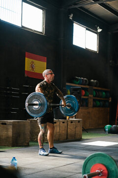 Strong man exercising with barbell in gym