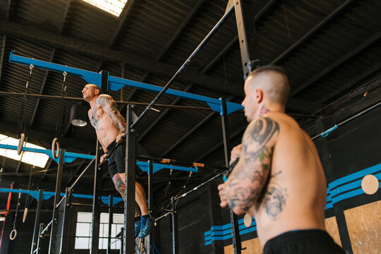 Male trainer looking at athlete on bar