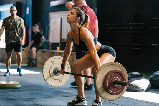 Sportswoman deadlifting barbell in gym