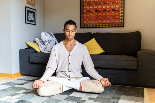 Young man relaxing at home doing meditation 
