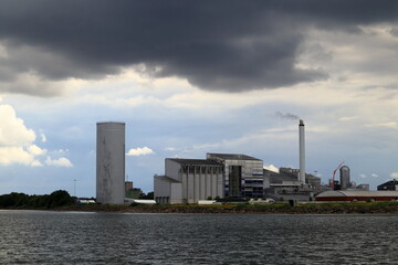 Industry by the water. Factory. Great and beautiful view in a far distance. Gray dark clouds in the sky. Copy space for extra text. At the Swedish lake Vänern or Vanern. Lidköping, Sweden, Europe.