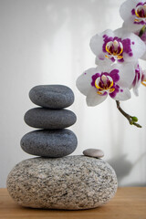 Fototapeta na wymiar Stack of gray stones built in tower isolated on white background with white purple orchid flower on long stem