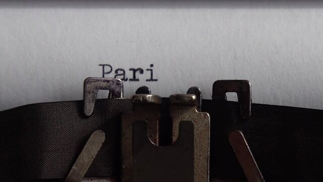 Typing city name Paris on an old typewriter. Close up.
