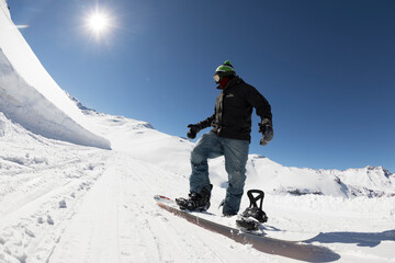 Snowboarder prepares to ride the backcountry on a bluebird sunny day in the snowy mountain during winter in Chile