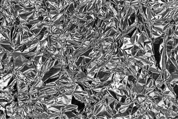 Thin sheet of silver leaf background with shiny crumpled uneven surface