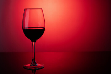Glass of red wine on a red background on the table