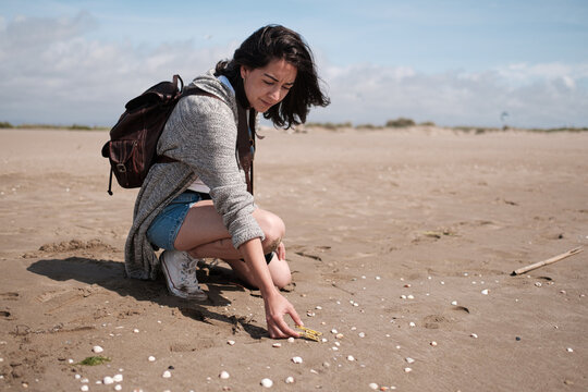 young woman cleaning the beach of plastics