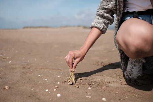 Faceless young woman cleaning the beach of plastics