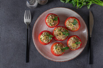 Tomatoes stuffed with tuna and olives on a white plate on a dark gray background. Copy space