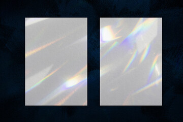 Two empty white vertical rectangle a4 poster, business card mockups with overlay of rainbow light refraction caustic effect and shadow on dark blue concrete background