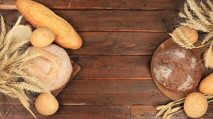 Freshly baked homemade sourdough bread with crispy crust and ears of rye and wheat on an old wooden background with place for text, modern bakery concept, top view, healthy natural food,