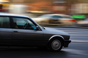 panning shot of a car with blurred background, taxi in the background symbolizing a busy street and dense traffic