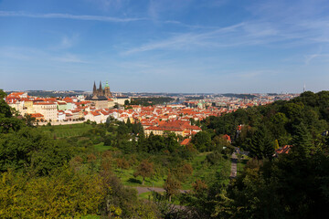 Fototapeta premium Autumn Prague City with gothic Castle and the colorful Nature with Trees from the Hill Petrin, Czech Republic