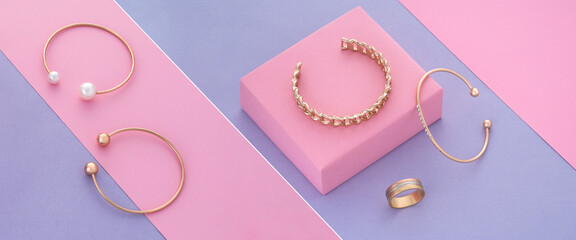 Slanted photo collage of gold bracelets and ring on pastel colors background