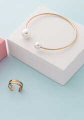 Vertical shot of Golden with pearls bracelet and double ring on white and blue background