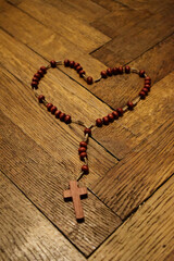 Czerwona koronka do Krwi Jezusa ułożona w kształcie serca na drewnianym tle