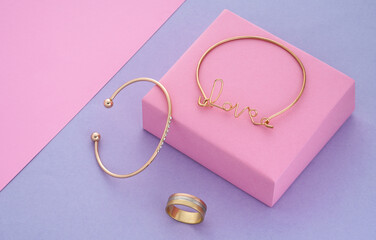 Love word shape bracelet and modern design bracelet and ring on pink and purple background with copy space