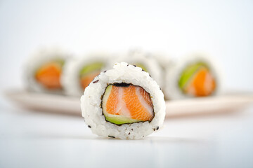 Fresh California sushi rolls with salmon, avocado and black sesame seeds on a light background close-up. © Andrey