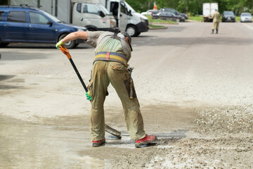Work with a shovel at a construction site. A worker throws cement and gravel with a shovel.