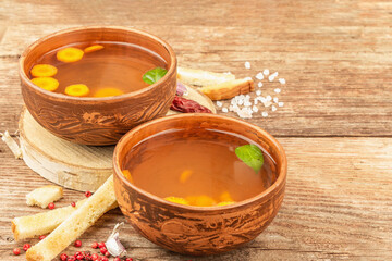 Transparent chicken broth with vegetables in ceramic bowls