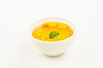 Transparent chicken broth with vegetables in ceramic bowls