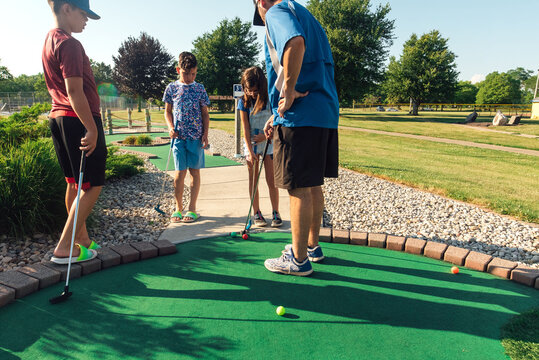 Father and kids measuring golf balls on the fairway. 
