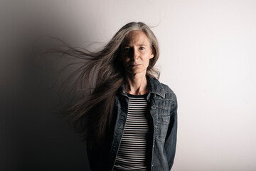 Modern senior woman with grey long hair flying