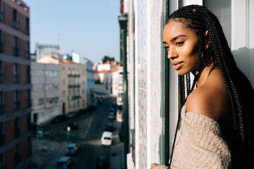 Beautiful black woman with braided long hair standing in a balcony