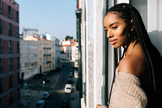 Beautiful black woman with braided long hair standing in a balcony