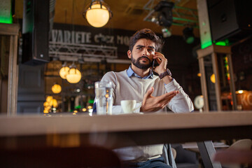 Handsome beard man in cafeteria talking on phone